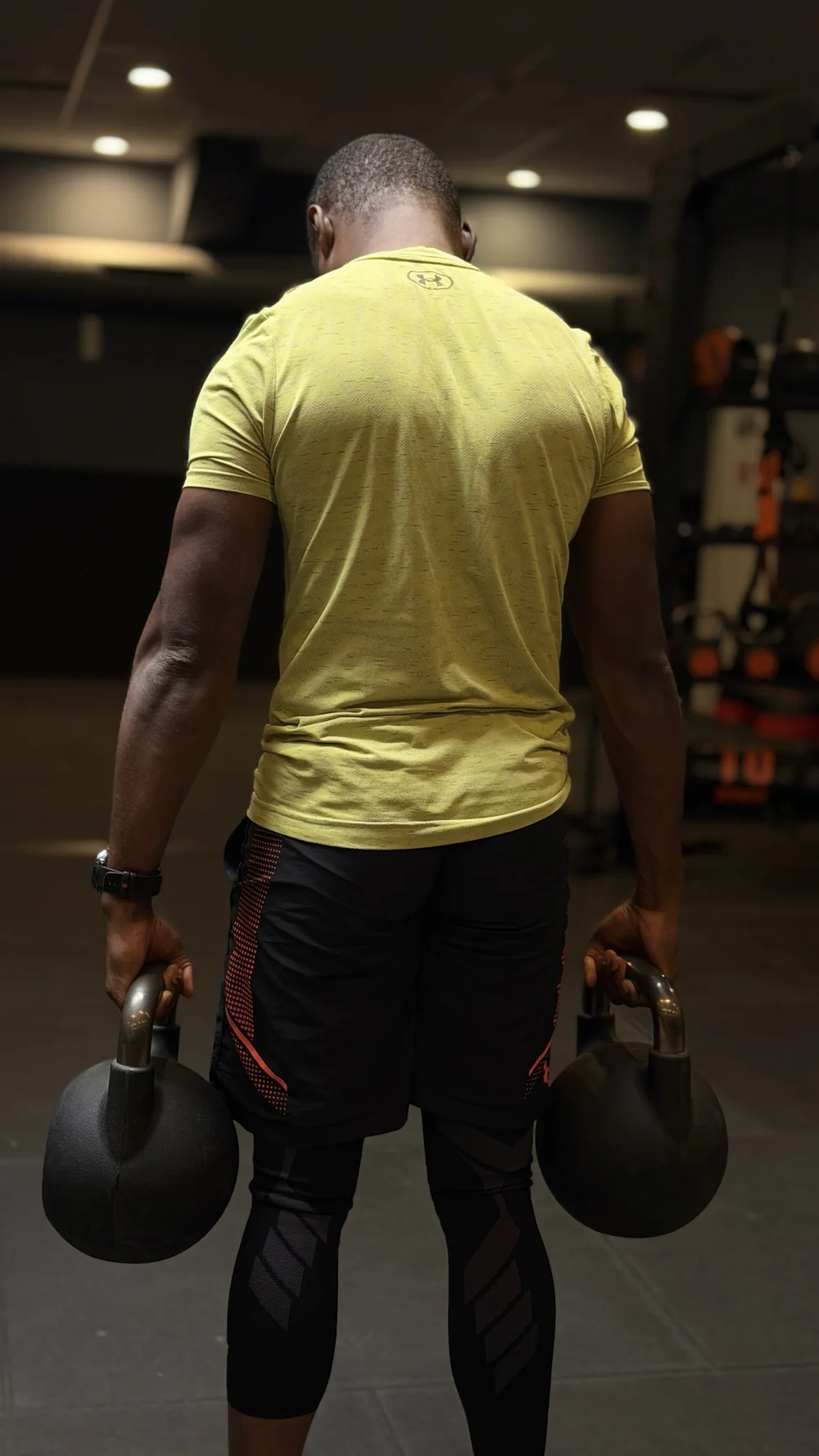 Bouba Ousmana en marche du fermier avec deux kettlebells, de dos